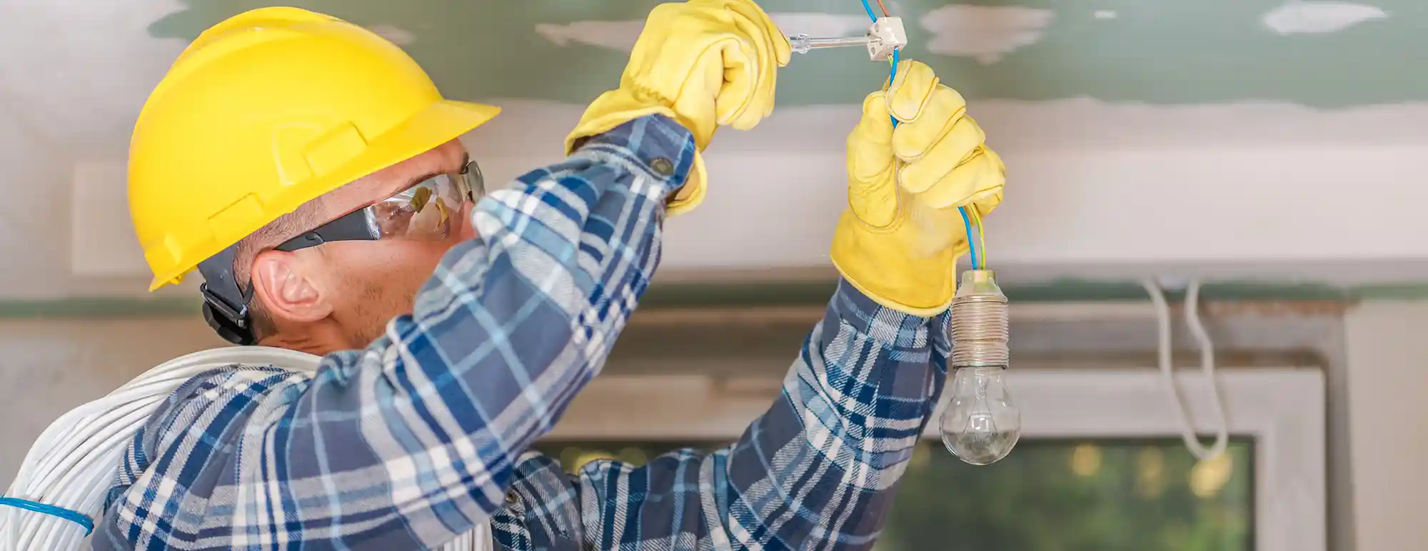 Electrician installing lighting fixture on the ceiling of a room