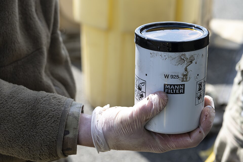 A person is holding a newly filled oil filter