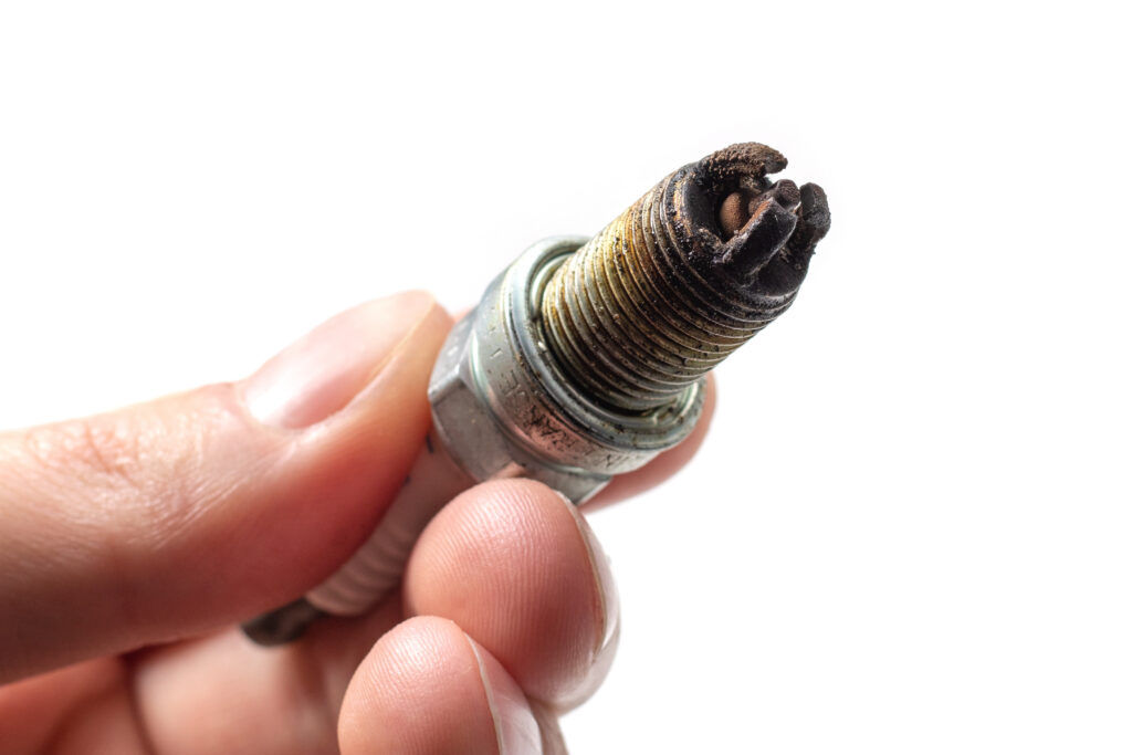 A person holds a dirty spark plug