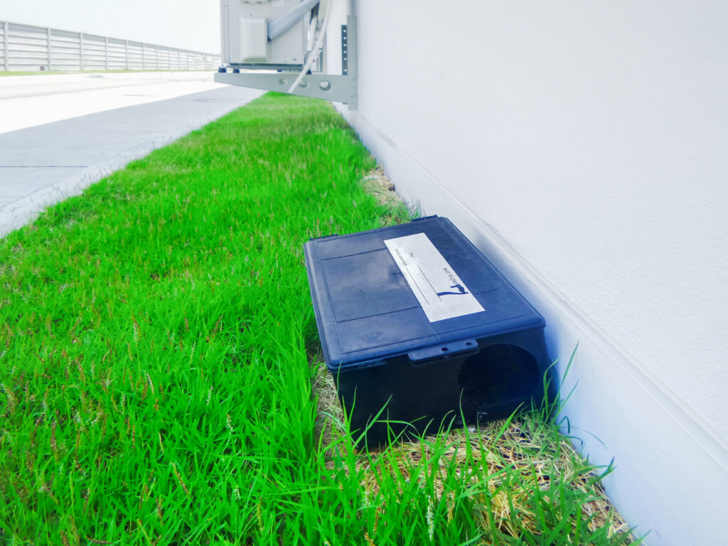 a bait station for mice sits in grass
